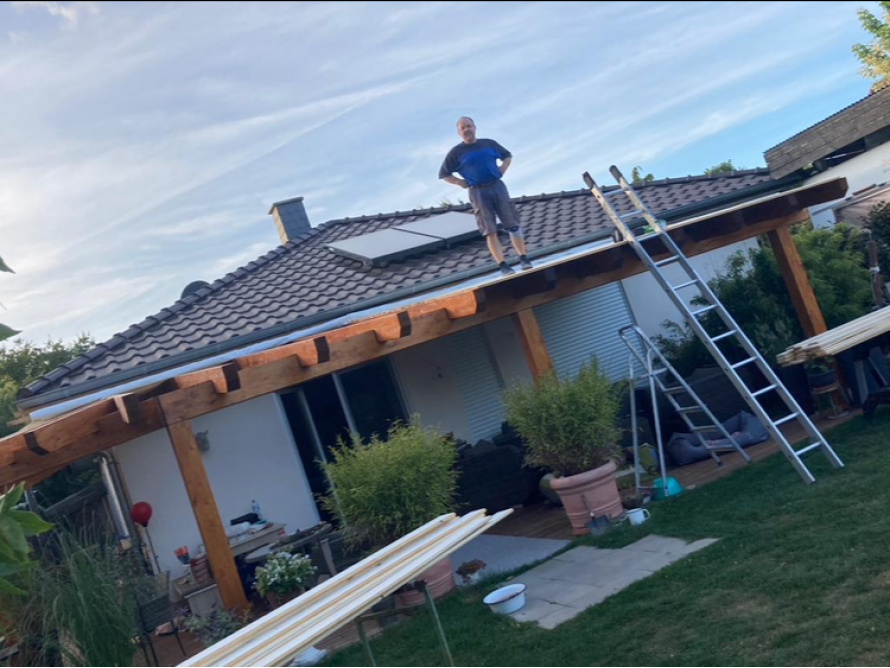 Person auf dem Dach einer Terrassenüberdachung