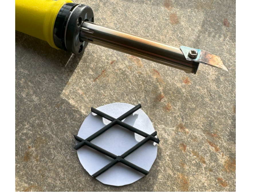 Lötkolben und Plastikgitter auf Tisch