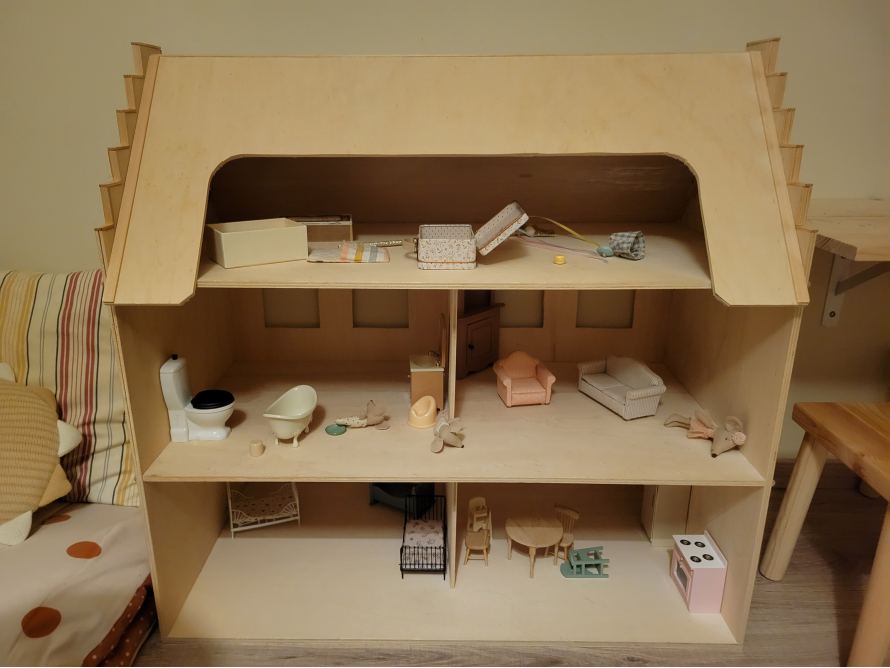 Ein unbemaltes Holzpuppenhaus mit drei Etagen.