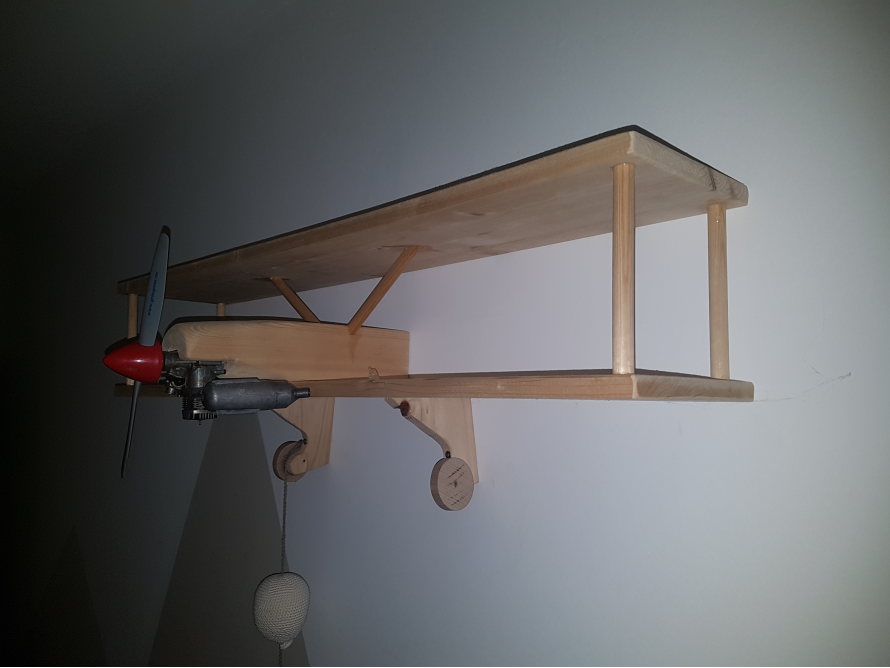 Ein hölzernes Flugzeugregal an einer Wand.