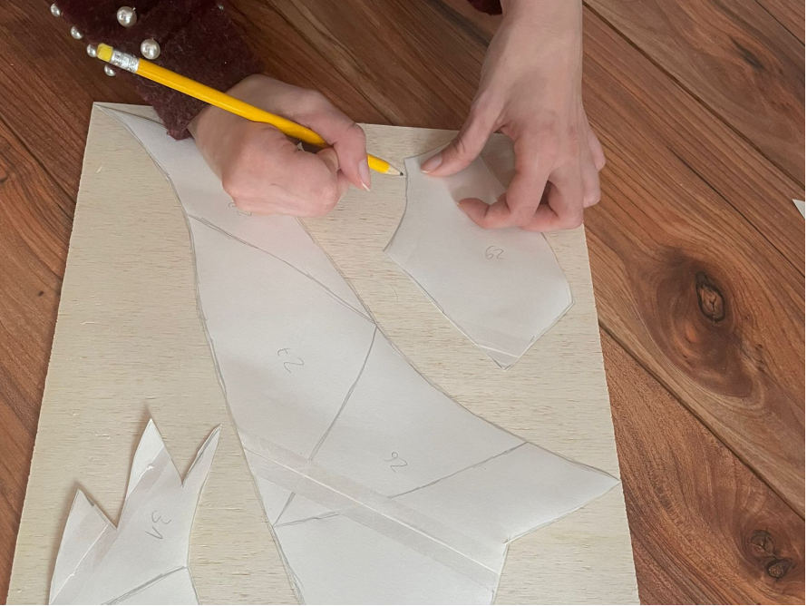 Hände zeichnen mit Bleistift Schnittmuster auf Holzbrett