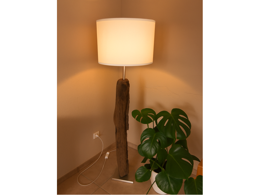 Eine beleuchtete Stehlampe mit einem Fuß aus Holz neben einer Zimmerpflanze.