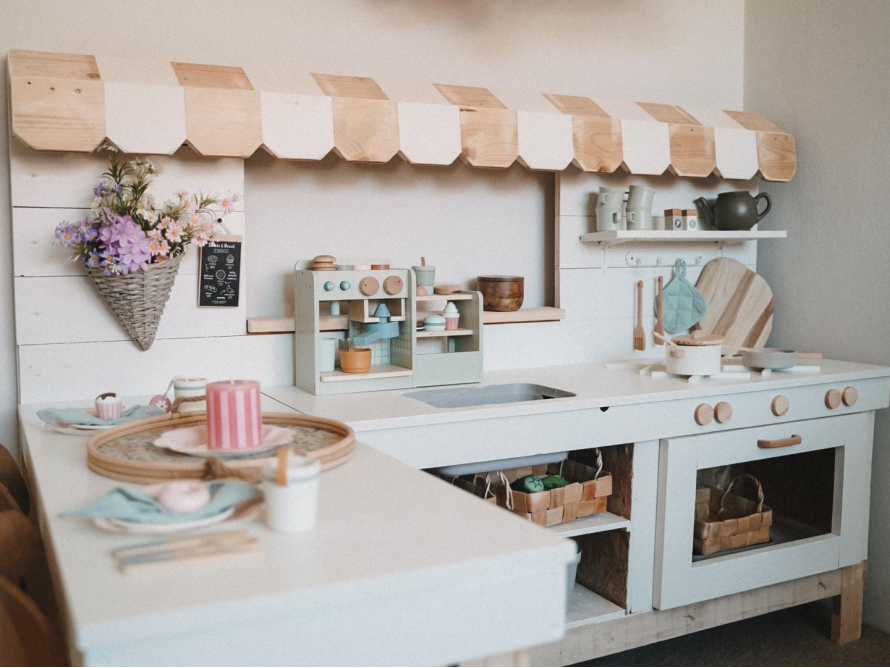 Eine weiße Spielküche aus Holz mit viel Zubehör.
