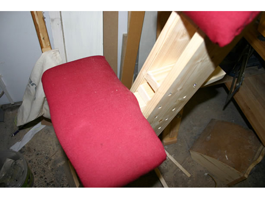 Holzgestell eines knienden Stuhls mit rotem Polster