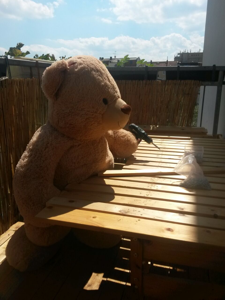 Teddybär baut mit Akkuschrauber ein Holzgestell